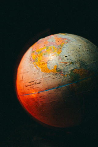 Abstract digital globe with connection lines linking Latin America to North America and Europe on a deep teal background.