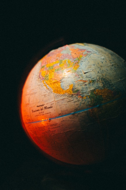 A globe displaying parts of North and South America with a warm red and orange light illuminating its surface. The text 'Naciones del Mundo' is visible on the globe, suggesting a Spanish label. The background is dark, emphasizing the glowing effect on the globe.