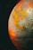 A close-up of a globe highlighting the North American continent, particularly the United States and Mexico. The surface has detailed geographical and political borders, with country names and cities marked. Warm, ambient lighting creates a cozy, vintage atmosphere, casting shadows and reflections on the globe’s surface.