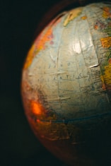 A close-up view of a globe with visible text in Spanish, showing parts of the Atlantic Ocean. The image is warmly lit, creating a nostalgic atmosphere.