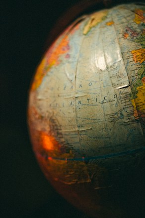 A close-up view of a globe with visible text in Spanish, showing parts of the Atlantic Ocean. The image is warmly lit, creating a nostalgic atmosphere.