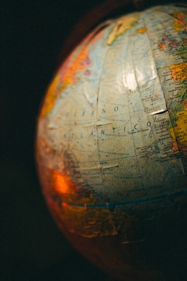 A close-up view of a globe with visible text in Spanish, showing parts of the Atlantic Ocean. The image is warmly lit, creating a nostalgic atmosphere.