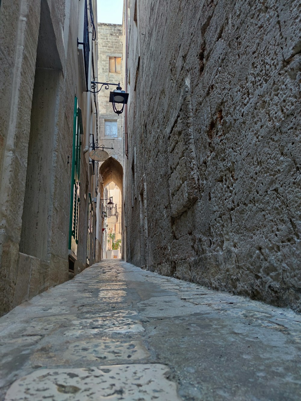 a narrow alley way with a light at the end