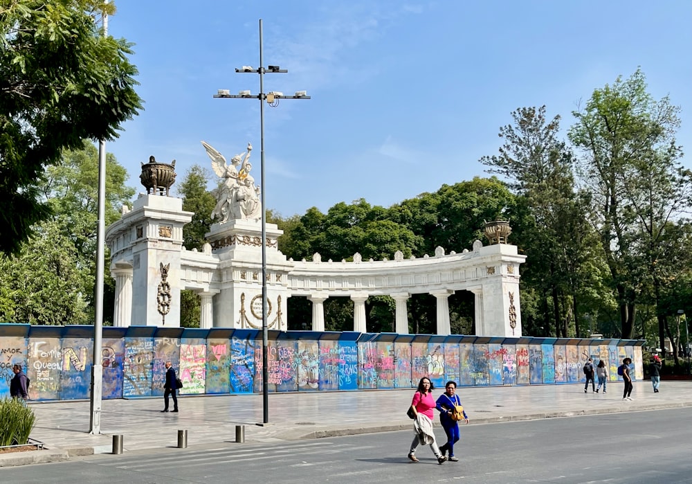 a group of people walking down a street next to a white building