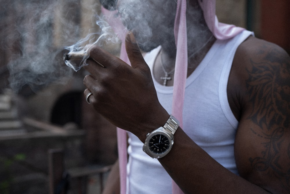 a man in a white tank top smoking a cigarette