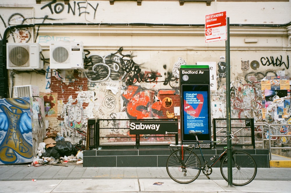 a bike parked next to a wall covered in graffiti