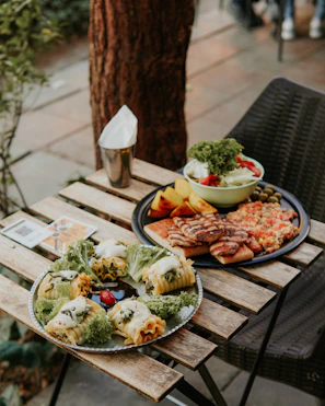 A rustic wooden table outdoors with a plate of tender beef stew steaming.