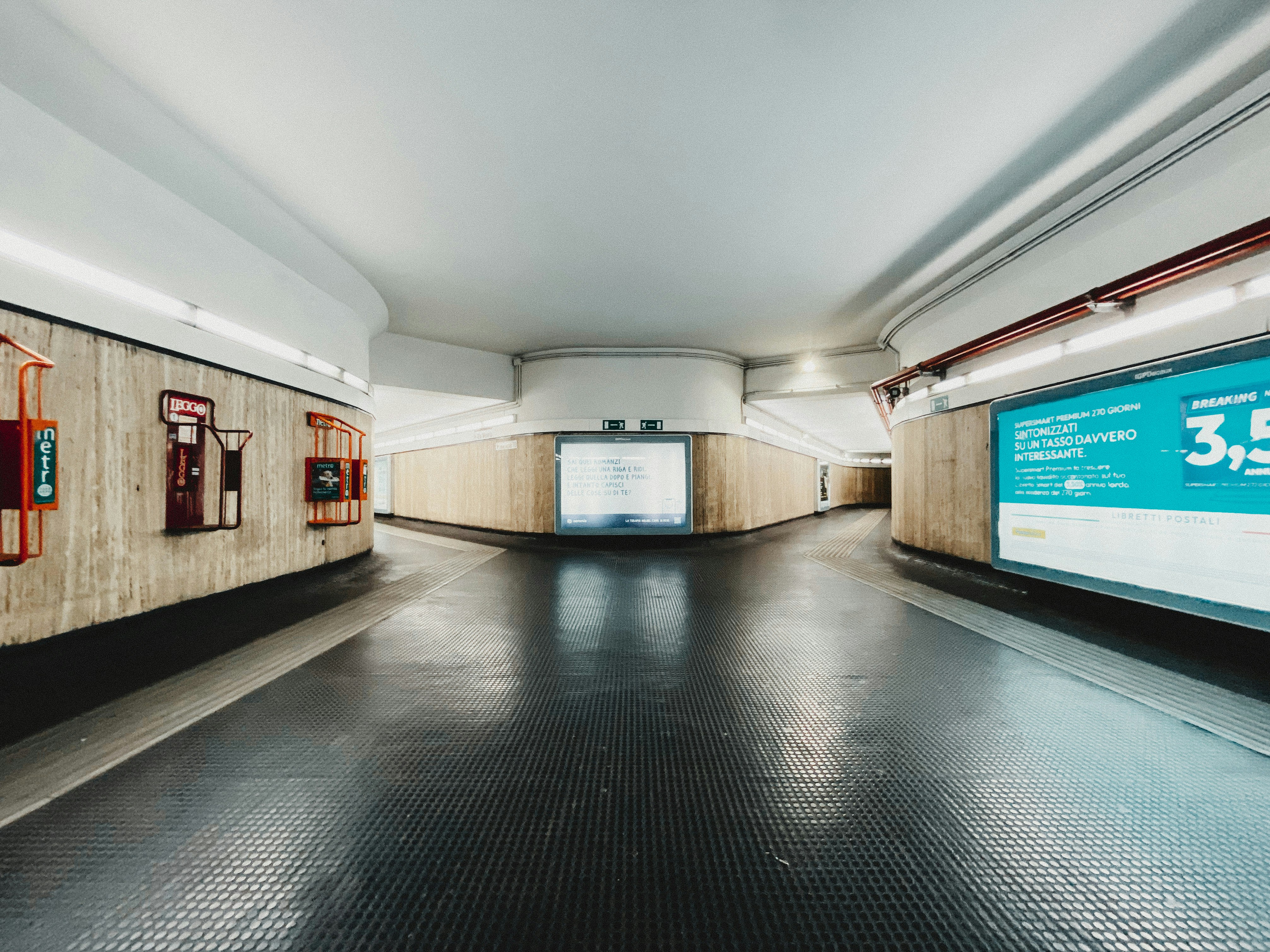 an empty subway station with a large screen on the wall, Rome underground station