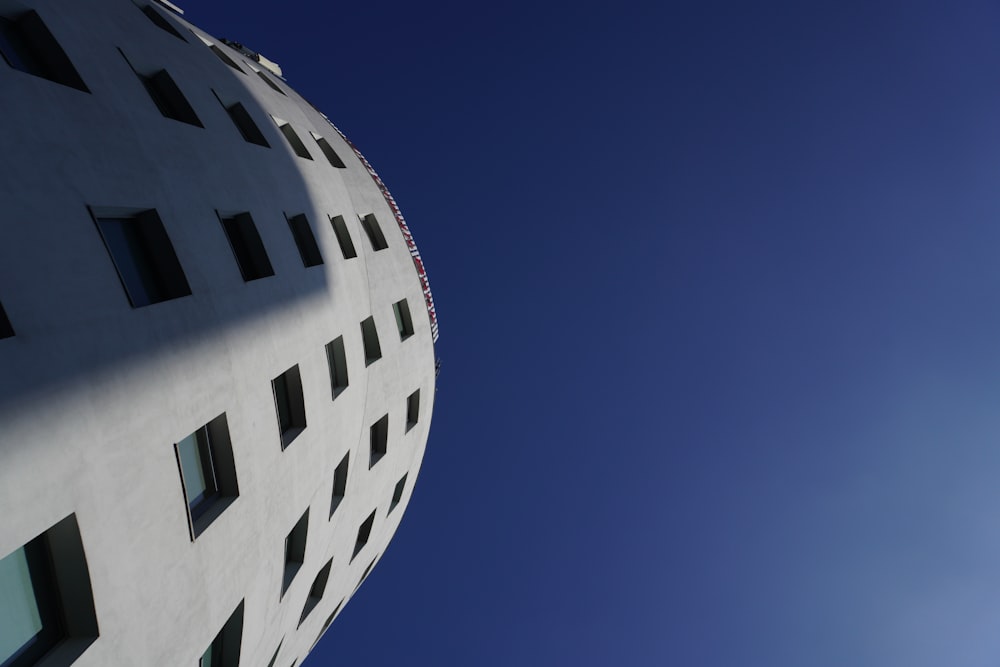 a tall white building with windows and a blue sky in the background