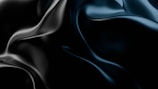 Smooth, fluid-like black and dark blue surfaces with reflective highlights create an abstract and dynamic appearance.