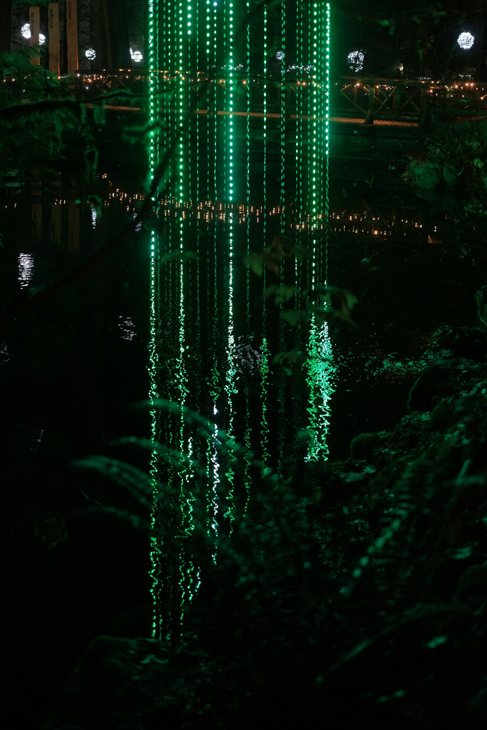 a green tower with lights reflecting in the water
