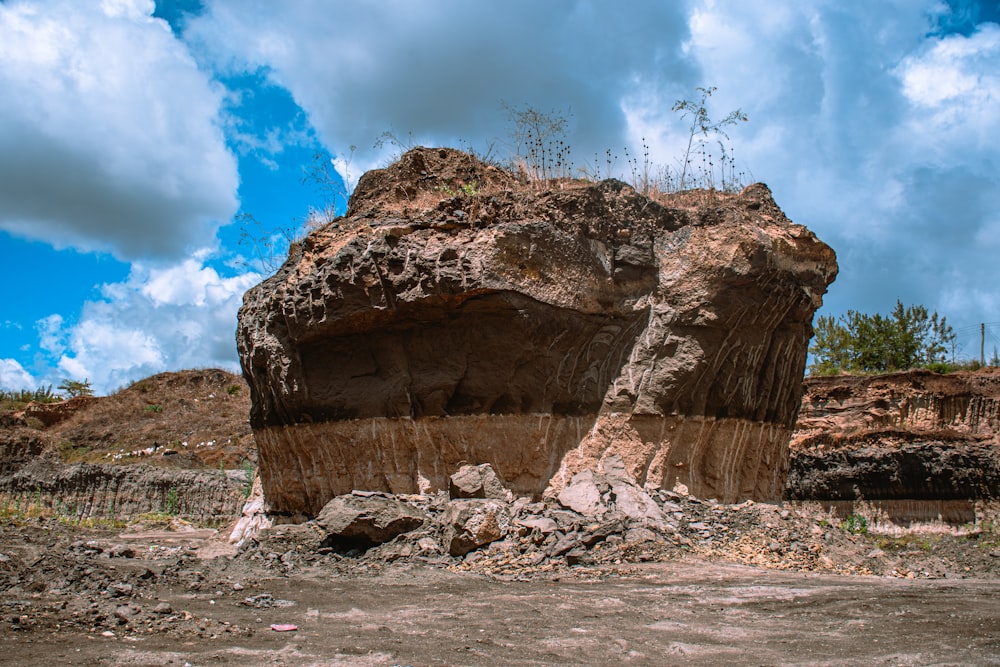 a large rock sitting on top of a dirt field