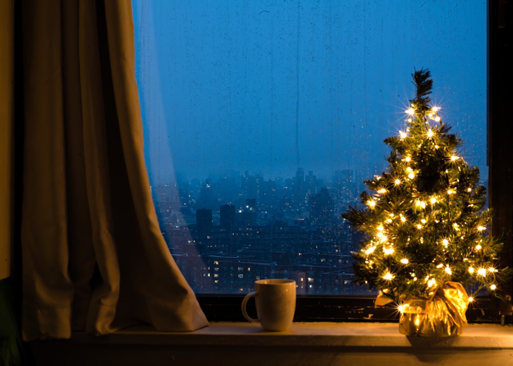 Un albero di Natale illuminato davanti a una finestra