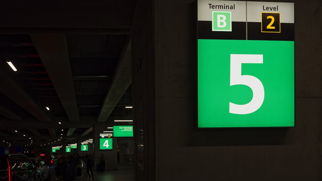 a green and white sign that says terminal level 5, number signs in front of the airport