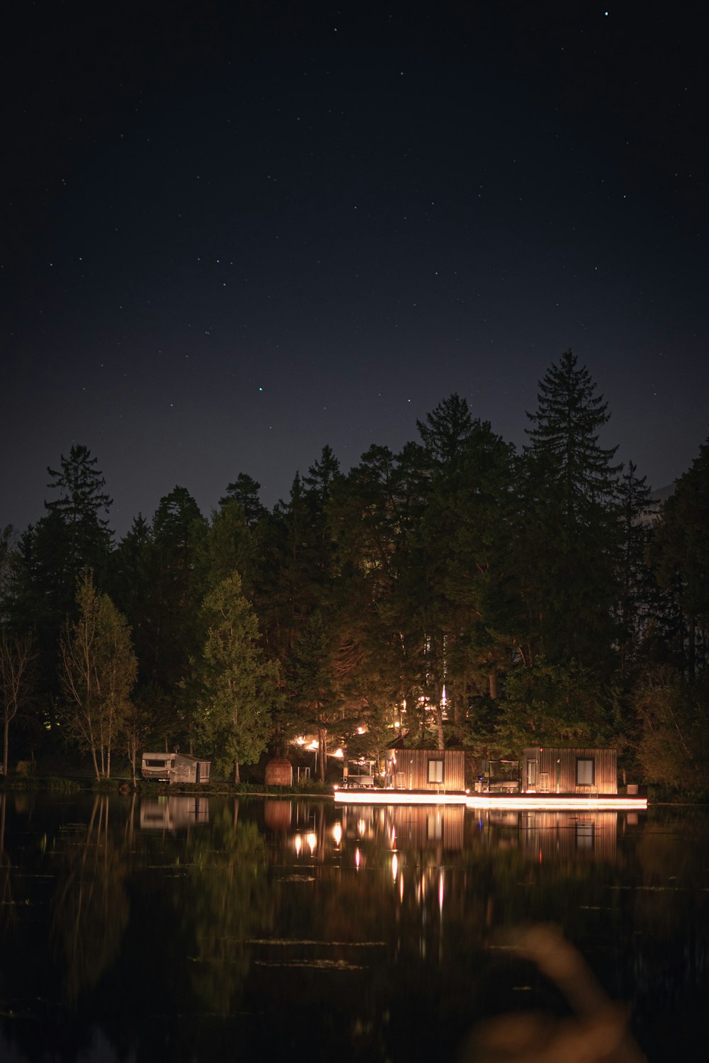 a house is lit up at night by a lake