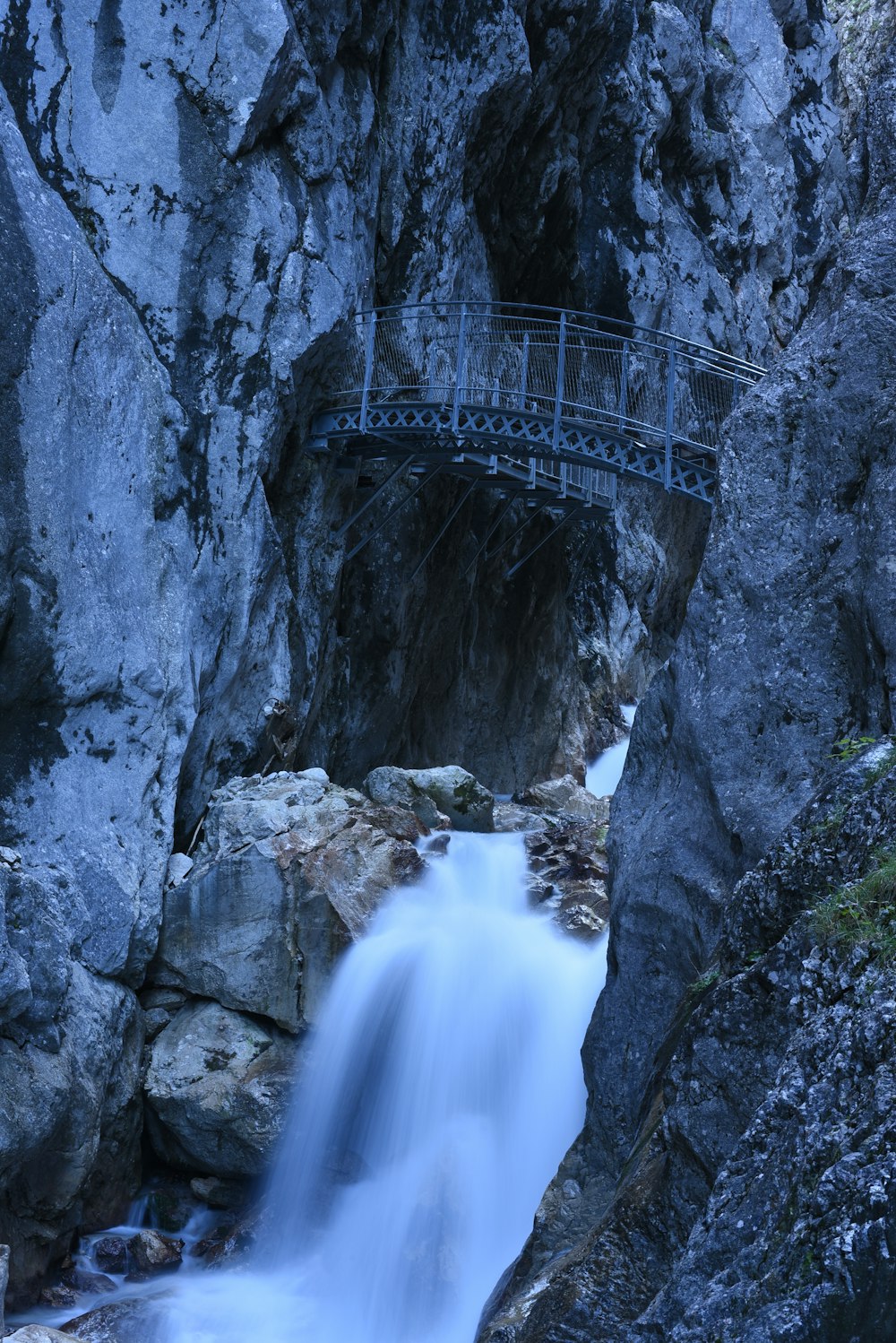 a bridge over a small waterfall in the mountains