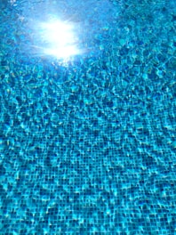 Close-up of a solar pool cover reflecting sunlight on a calm pool surface.