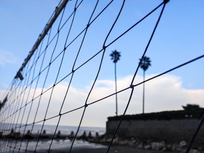 Close-up of hands setting a volleyball against a clear blue sky.