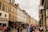A busy street scene with people walking past various local businesses.