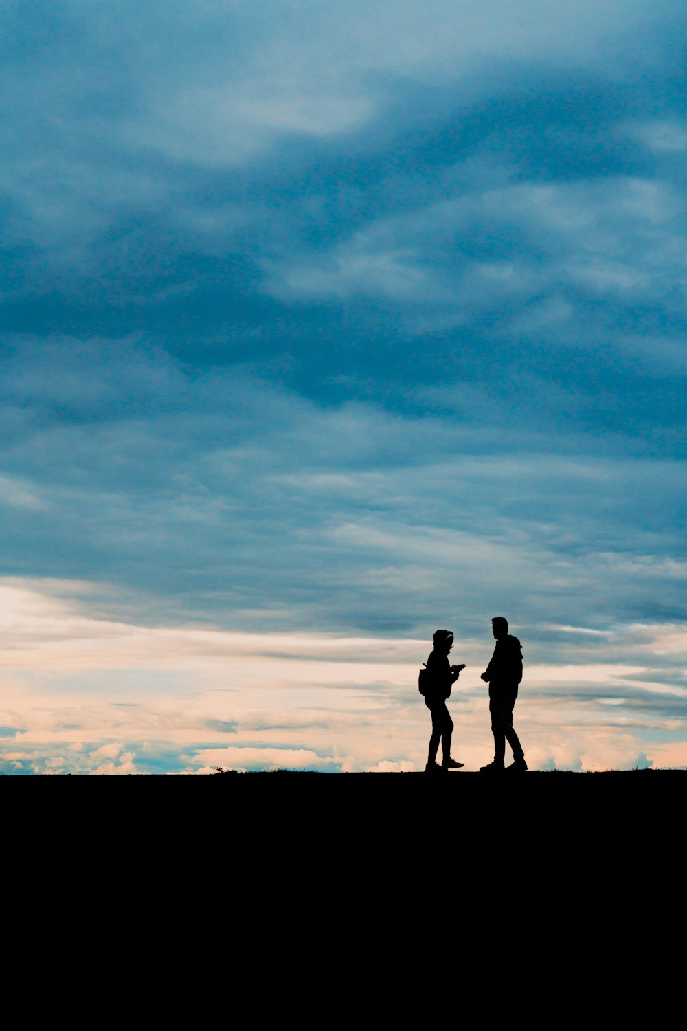 um casal de pessoas em pé no topo de uma colina