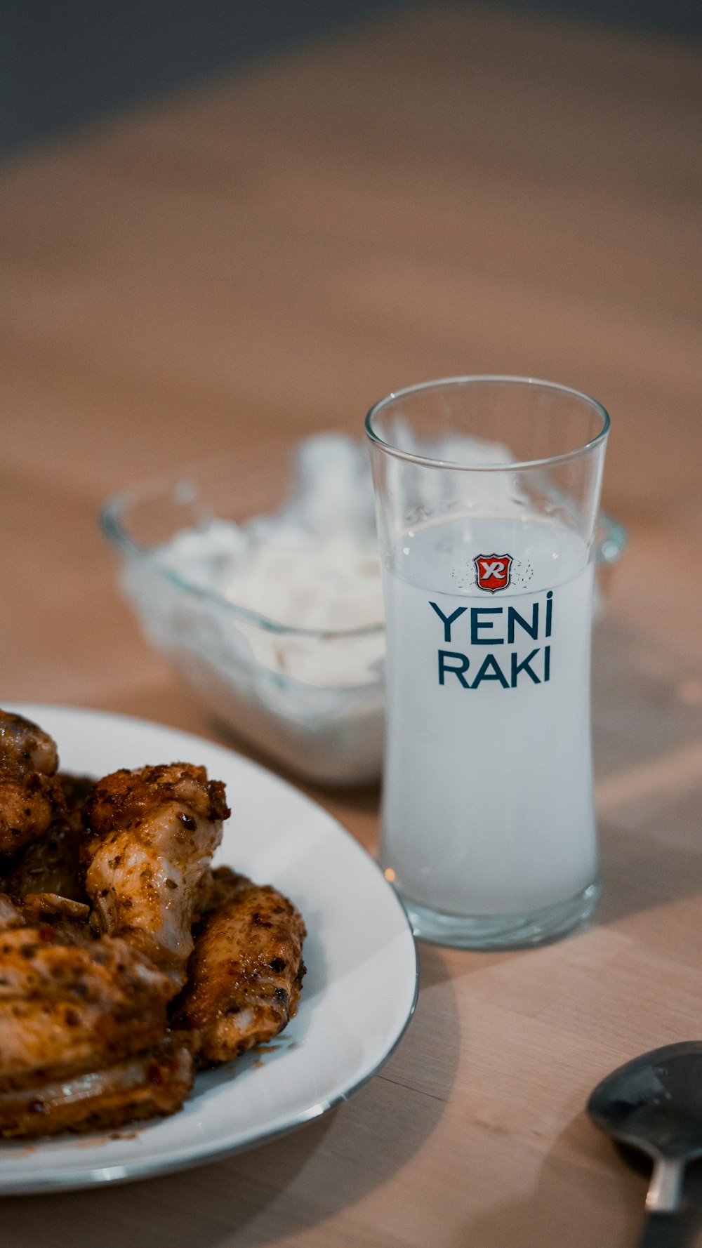 a plate of chicken wings next to a glass of yogurt