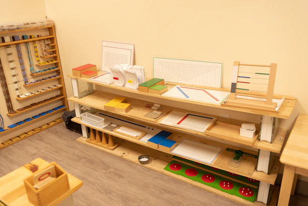 A bright, inviting Montessori classroom corner with wooden learning toys and colorful materials neatly arranged.