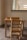 A small wooden table and chair set placed against a wall, with a window partially visible behind it. On top of the table, there is a wooden educational toy with small pegs, possibly for sorting or counting.