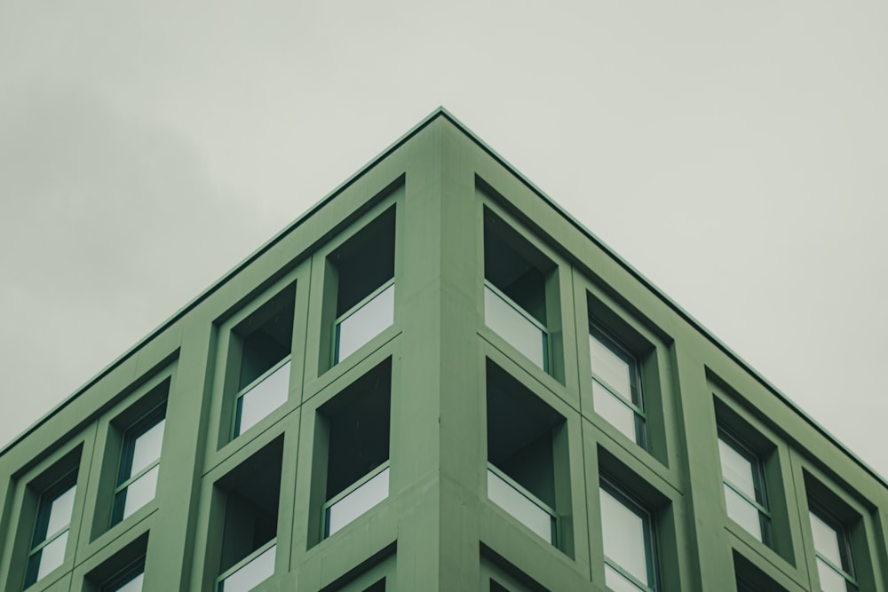 a green building with windows and a sky background