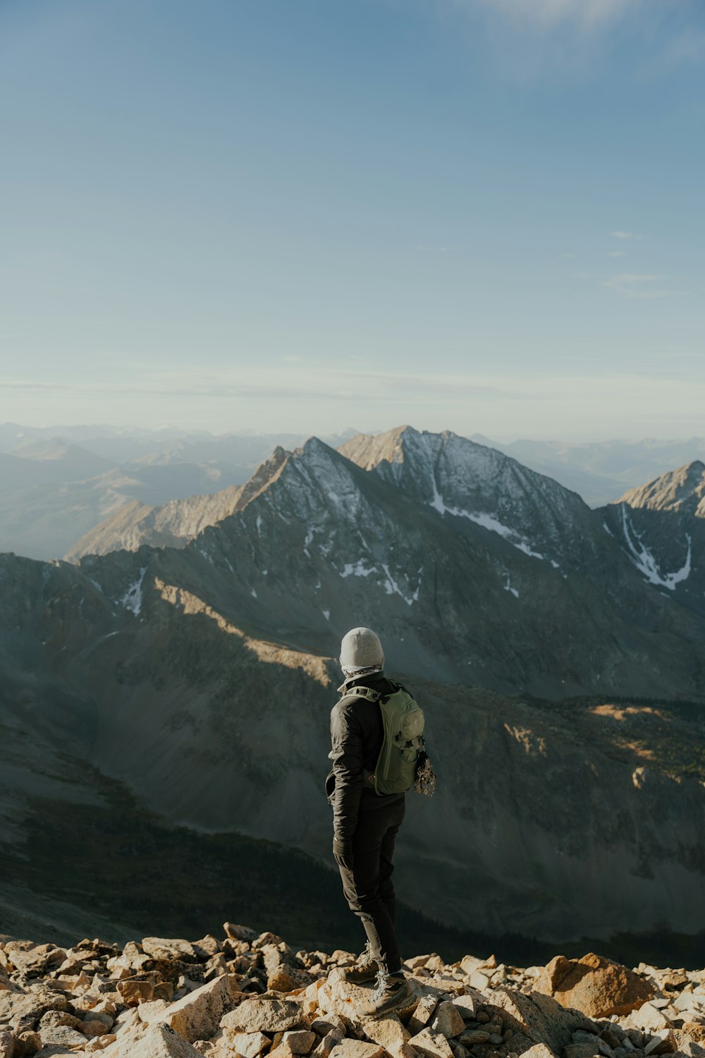 uma pessoa com uma mochila em pé no topo de uma montanha