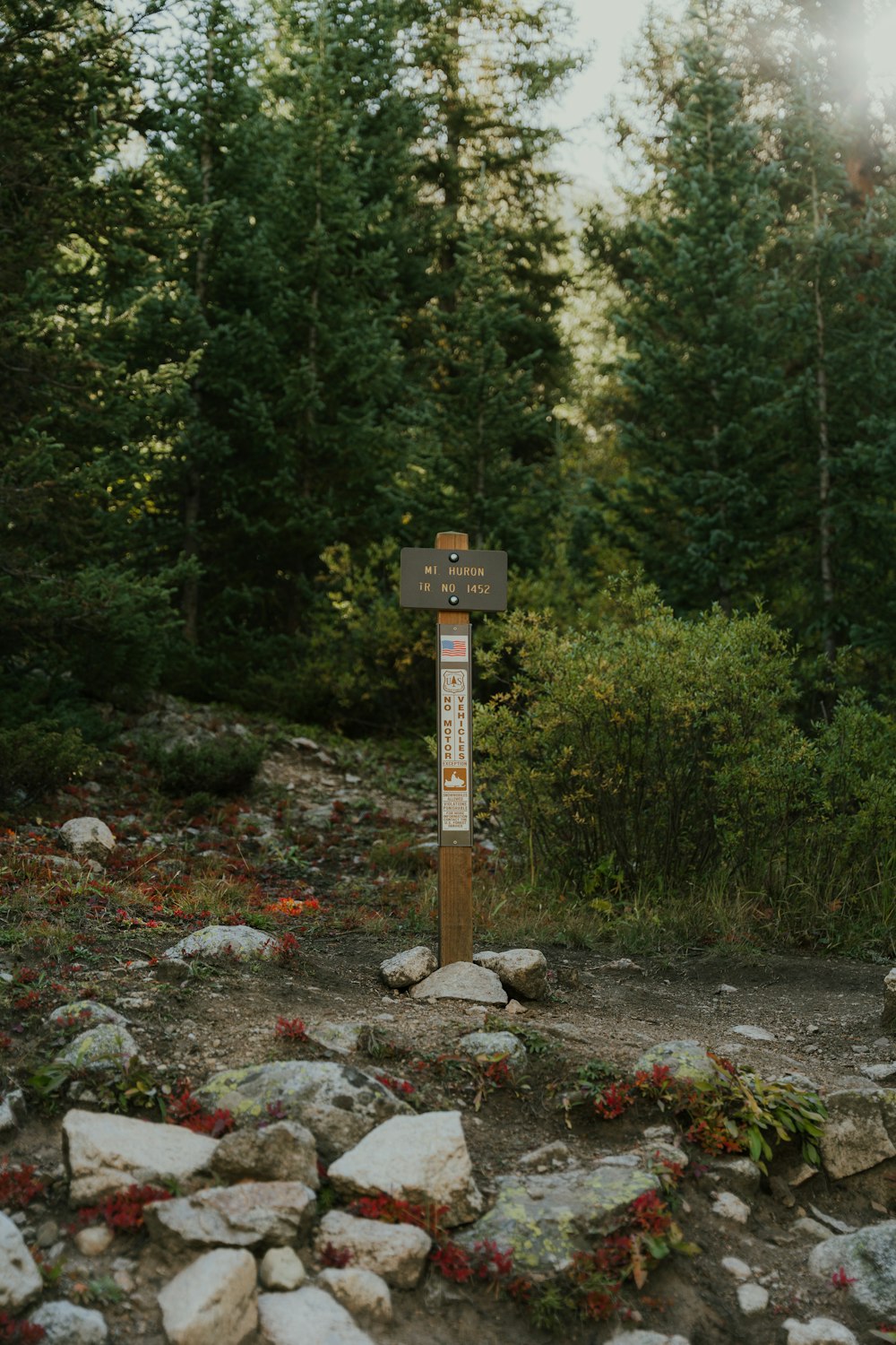 a wooden sign sitting on the side of a dirt road