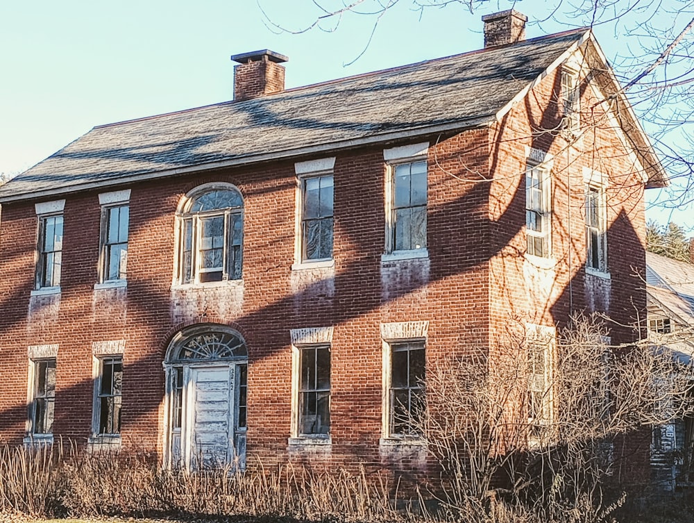 an old red brick house with boarded windows