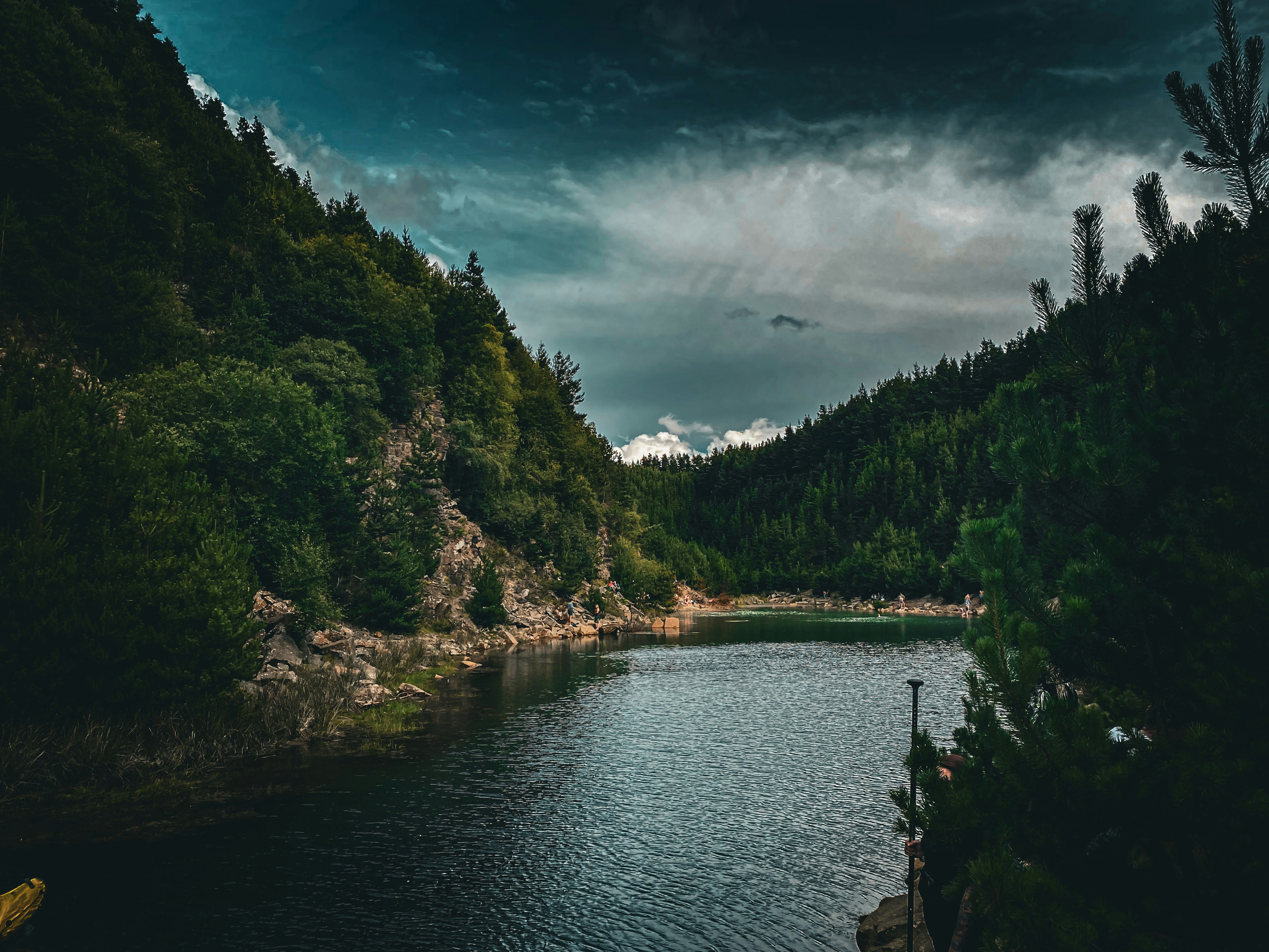 Patagonian granite towers with storm clouds, dark teal lake, dramatic low-light landscape
