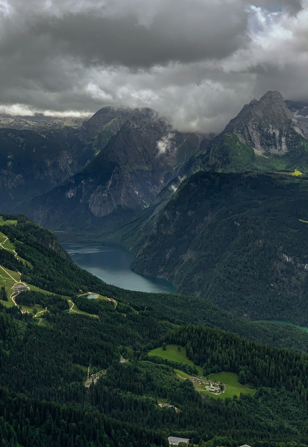 a scenic view of a valley with a lake and mountains in the background