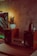 A cozy setup featuring a stereo system with wooden speakers and a central control unit placed on a wooden table. A small potted plant sits on top of the left speaker, while a decorative vase with reed diffusers is on the right. The background wall has a textured finish, adding to the warmth of the scene, illuminated by soft ambient lighting.
