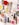 Various wellness and beauty products, including oils in bottles, a bowl of oil, dried flowers, crystals, a smudge stick, and a small dish of cream, are arranged aesthetically on a light surface. The scene is decorated with colorful flowers and herbs.