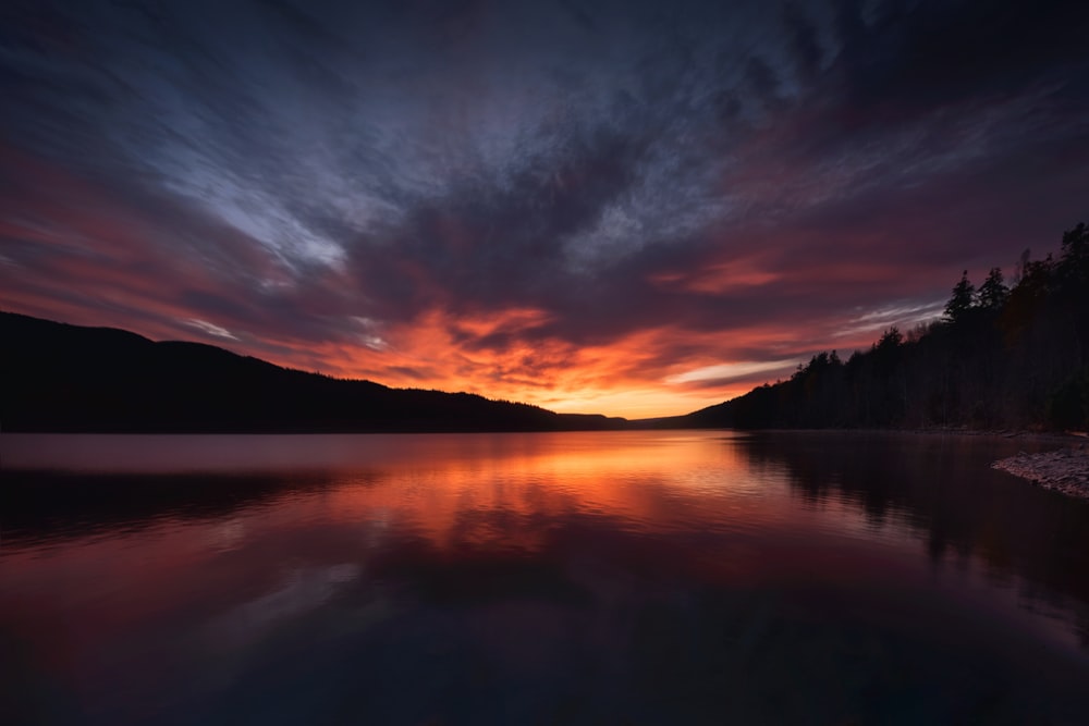 a beautiful sunset over a lake with mountains in the background