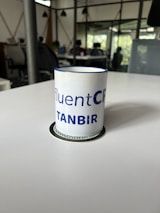 Entrepreneur holding a black and gold mug, smiling confidently in a sunlit office with modern decor.