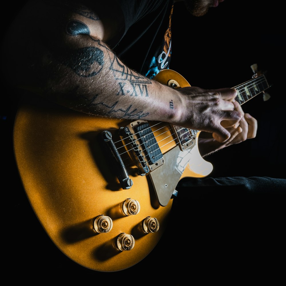 a man with a tattooed arm playing a guitar