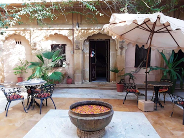 A peaceful courtyard with blooming flowers and rustic furniture, perfect for relaxing.
