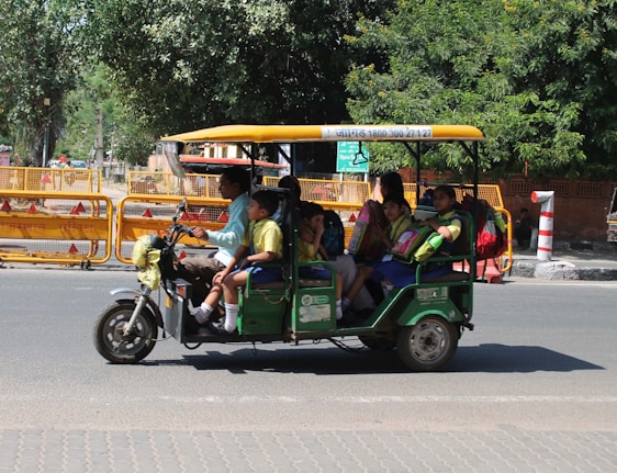 A young person happily operating an e-rickshaw in a clean, green urban environment.