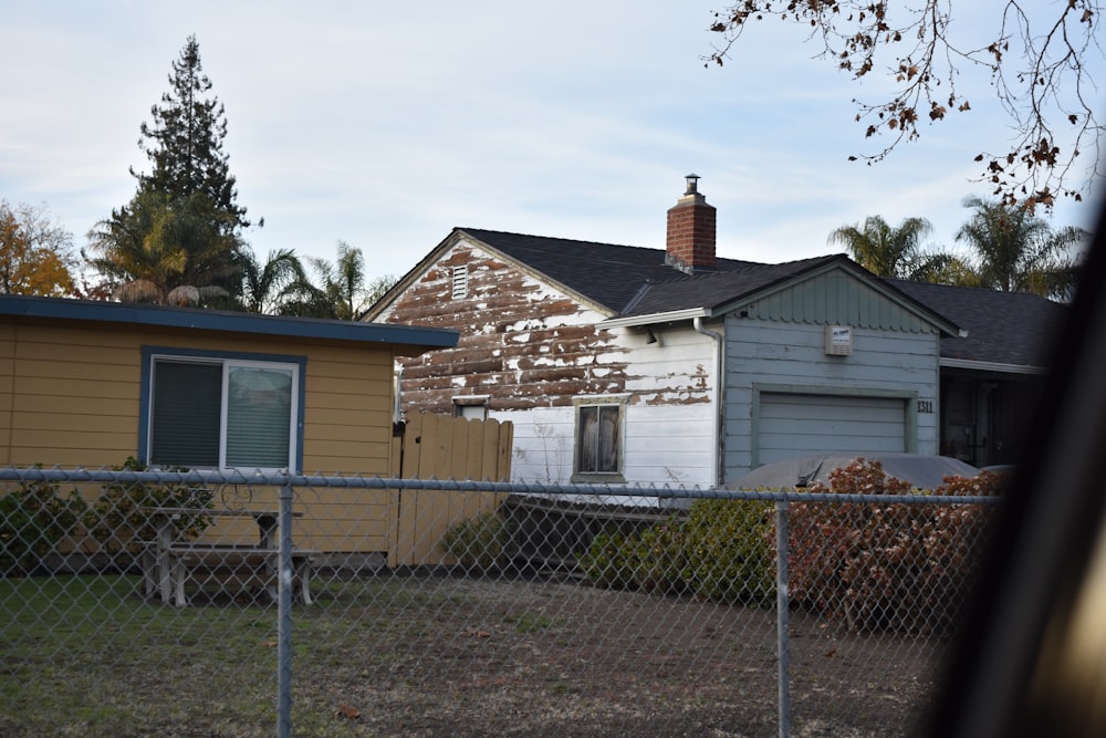 a house behind a chain link fence with a house in the background