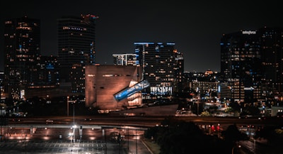 A striking nighttime cityscape featuring modern buildings illuminated against a dark sky, showcasing 青石建設's architectural projects.