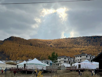 A serene landscape of Central Asian mountains with artists and learners gathered outdoors, sharing ideas.