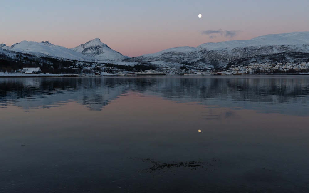 a full moon is seen over a mountain range