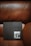 A black hardcover book titled 'H-VILLA' rests on a brown leather chair. The book features a square image on the cover showing part of a building with a roof and columns.