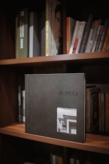 A stack of photo albums with handwritten labels on a wooden shelf.