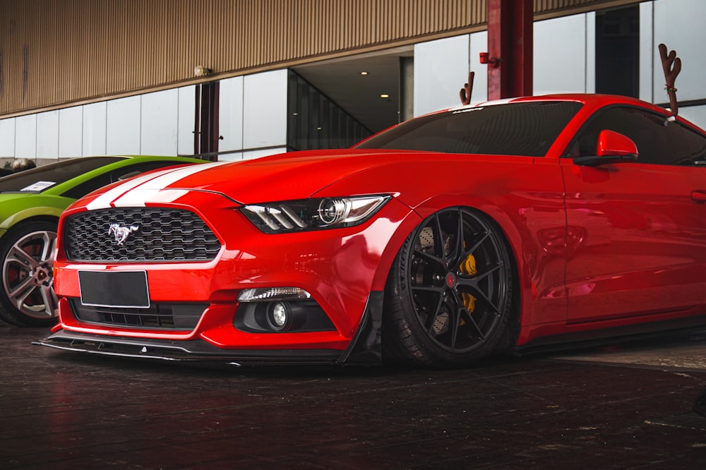 a red mustang mustang parked in front of a green mustang mustang