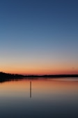 A serene outdoor shot of a solo founder reflecting by a quiet lake at sunset.