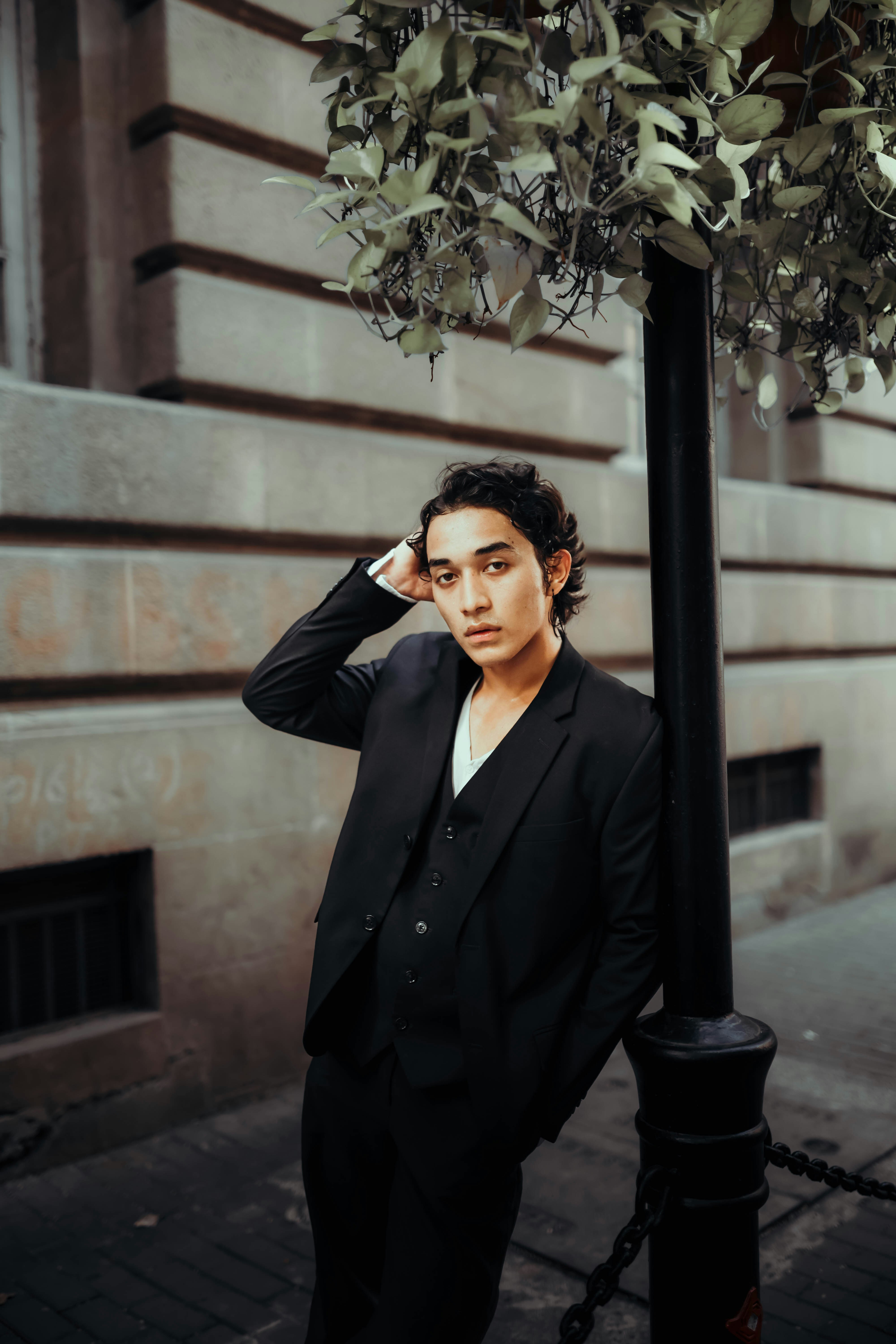 A man in a suit leaning against a pole photo – Free Man Image on Unsplash
