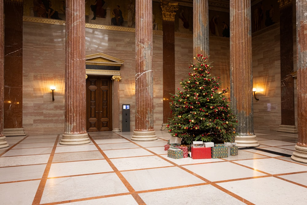 Uma árvore de Natal em uma grande sala com colunas